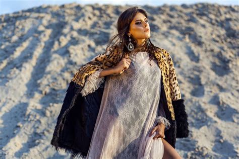 Attractive Brunette Woman In Translucent Beach Cover Up With Leopard Fur Coat Posing On Sandy