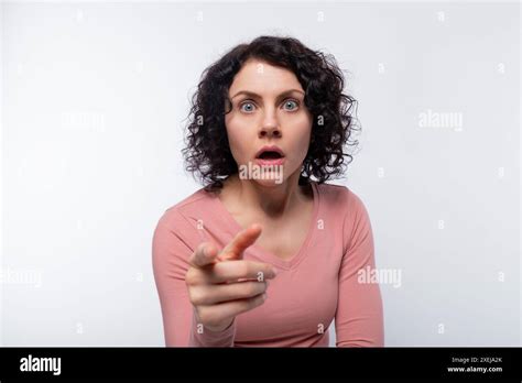 Brunette With Curled Hair Dressed In A Pink Blouse Holds Her Index Finger At The Camera Stock