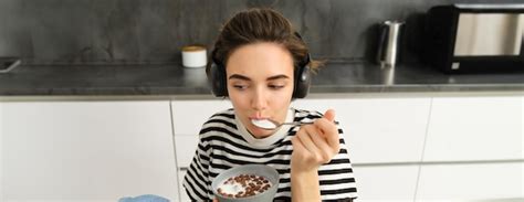 Premium Photo Cute Brunette Girl Student Eats Her Cereals With Milk For Breakfast Holding