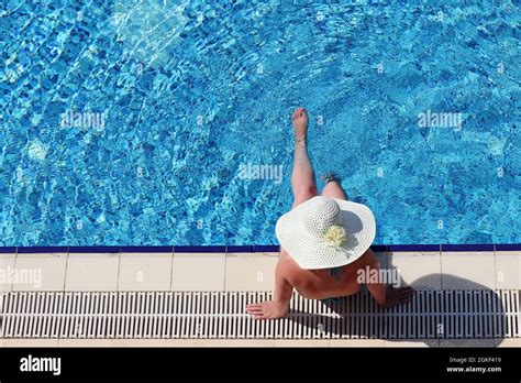 Frau In Bikini Und Sonnenhut Sitzt Am Rand Des Schwimmbades Und Baumelt Ihre Beine Im Wasser