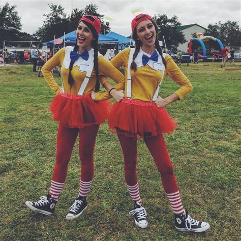 Two Women Dressed In Costumes Standing Next To Each Other On The Grass