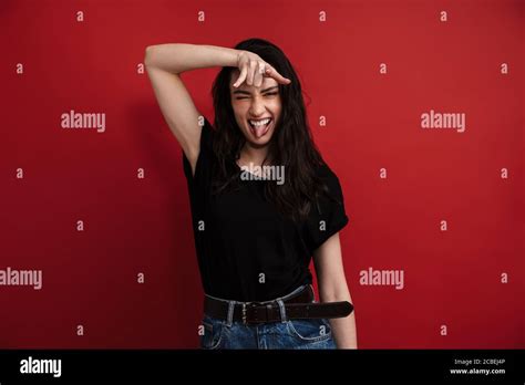 Photo Of Brunette Funny Woman In Casual T Shirt Winking And Showing Horn Sign Isolated Over Red
