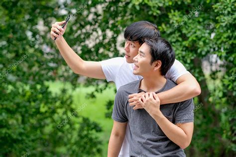 asiático gay pareja tomar foto selfies de sí mismos juntos en balcón con verde árbol fondo y día