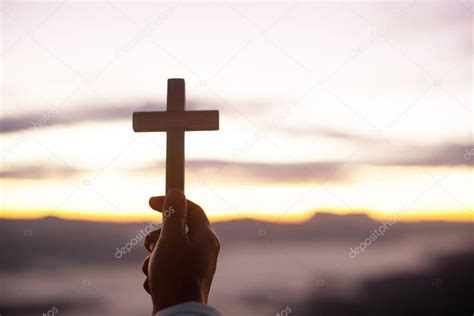 Manos Sosteniendo La Cruz De Madera Sobre El Fondo Del Amanecer