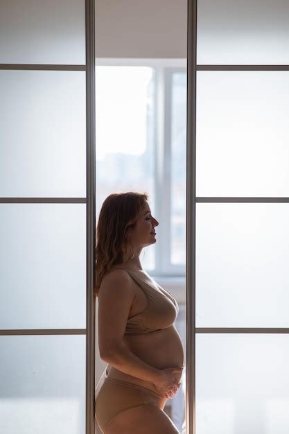 Premium Photo A Pregnant Woman In Nude Lingerie Stands In Profile Between Folding Doors