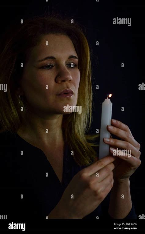 Portrait Of A Beautiful Blonde Woman Blowing Out The Flame Of A Candle