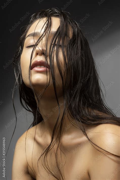 Beautiful Brunette Girl Fashion Model With Naked Shoulders And Wet Hair On A Gray Background
