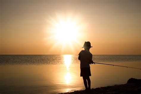 Un niño pescador feliz pescando en el mar en el viaje de silueta de la