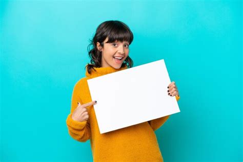 Jovem mulher latina isolada em fundo azul segurando um cartaz vazio expressão feliz Foto