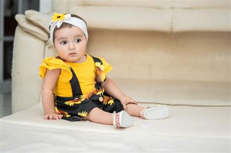 Premium Photo Baby Latina Sitting And Looking Away Curiously Is Wearing A Yellow Dress