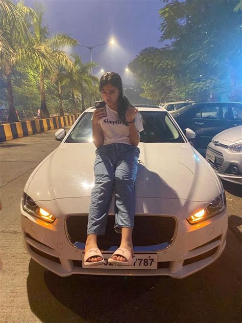 A Woman Sitting On The Hood Of A Car