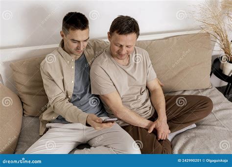 Feliz Pareja Gay Con Ropa Informal Pasando Tiempo Juntos En Casa Y Viendo Algo En El Smartphone