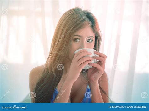 Female With Lingerie Is Drinking Breakfast Coffee In Her Bedroom Stock