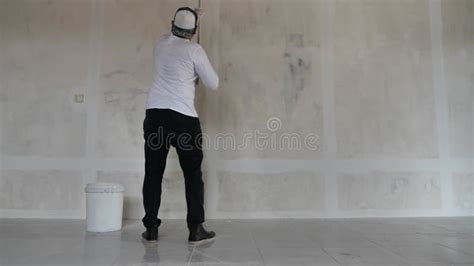 Asian Male Painter Painting New White Wall With Roller Brush Stock