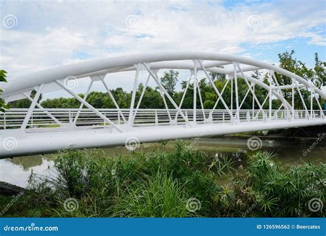 White Painted Truss Bridge Over River In Cloudy Summer Morning Stock
