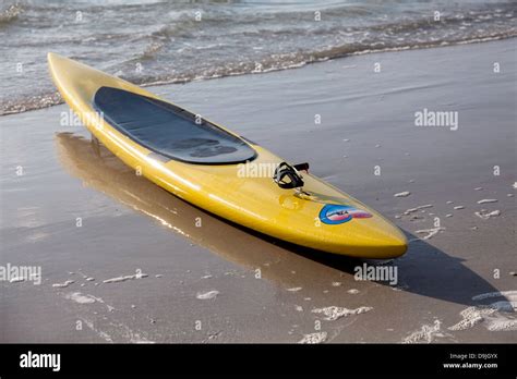 Yellow Ocean Sea Kayak Sitting On Beach At The Surf Line Stock Photo