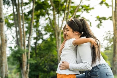 Junge Latina Mutter Auf Ihren Knien Umarmt Stolz Ihren Kleinen Sohn W Hrend Sie In Einem Park