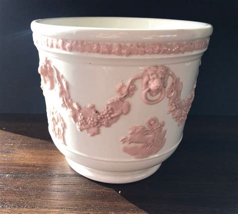 A White And Pink Vase Sitting On Top Of A Wooden Table