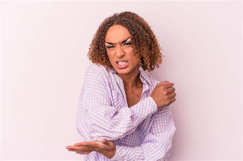 Jovem transexual latina isolada no fundo rosa massageando o cotovelo sofrendo após um mau