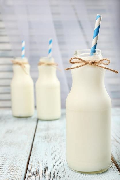 Premium Photo Milk In Bottles With Paper Straws On Table