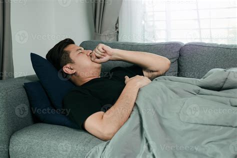 Asian people feel unhealthy while lying on the sofa at home while he