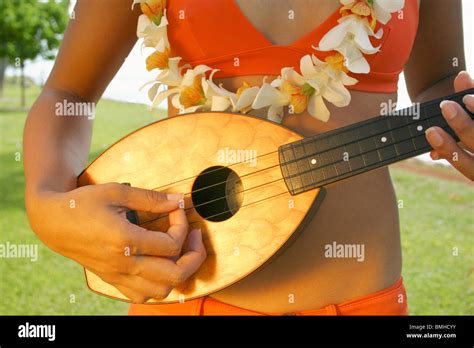 Closeup Of Hawaiian Woman In Orange Bikini With Orchid Lei Playing Pineapple Ukulele In Park
