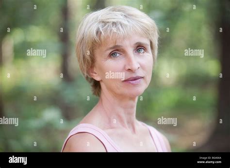 Mature Woman Stands In Forest Looking At Camera Stock Photo Alamy