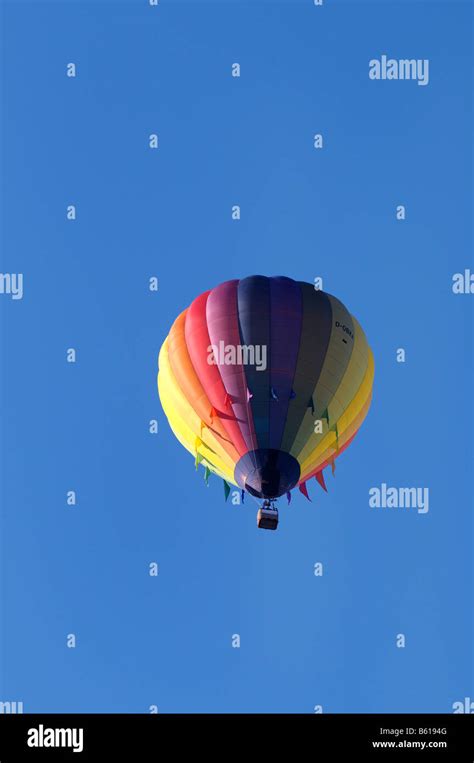Rainbow Coloured Tethered Or Captive Hot Air Balloon Against A Blue Sky Stock Photo Alamy