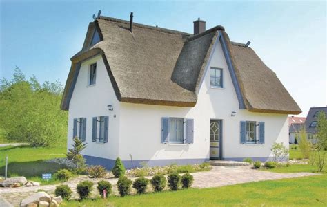 A Large White House With A Thatched Roof And Windows On The Grass Lawn