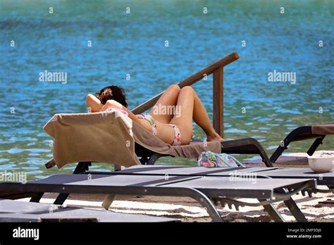 Woman In Bikini Sunbathes Lying In Lounge Chair On Sea Background