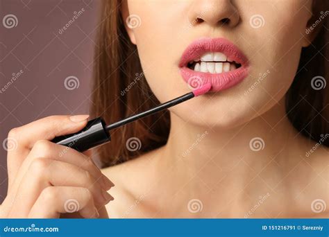 Beautiful Young Woman Applying Pink Lipstick On Color Background