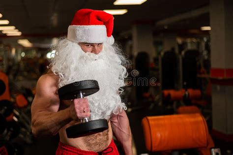 Santa Claus In The Gym Muscular Man With A Naked Torso Doing Exercises