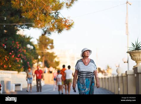 Elegant Mature Woman Walking On Promenade During Summer Sunset In Park Portrait Of Elederly