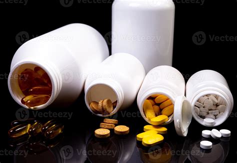 Medical pills flow from a white jar on an isolated black background