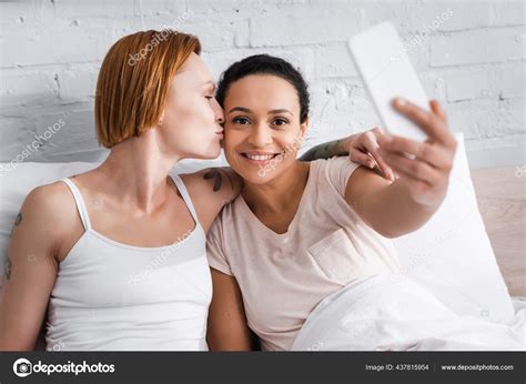 Redhead Lesbian Woman Kissing African American Girlfriend Taking Selfie Smartphone Stock Photo