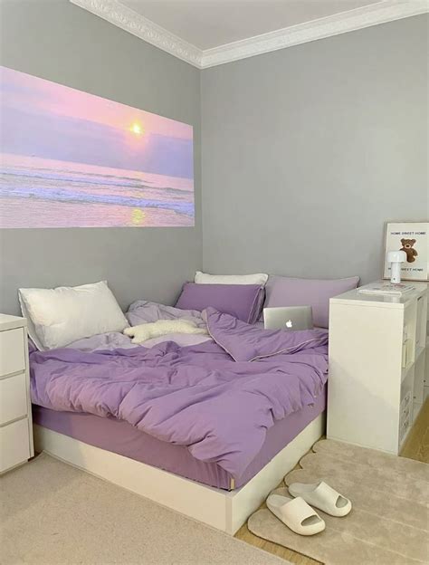 A Bed With Purple Sheets And Pillows In A Bedroom Next To A Painting On