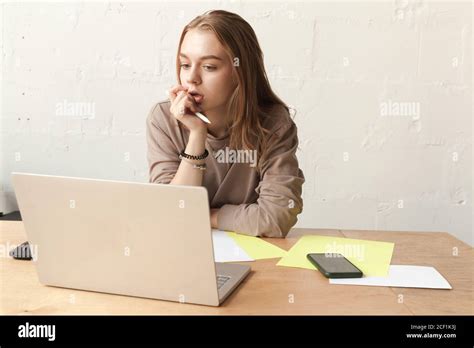 Jeune fille étudiante blonde pense est dans une salle de classe avec un ordinateur portable un