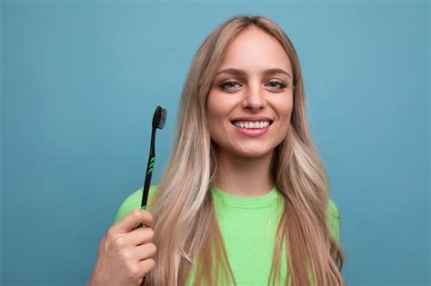 Jeune Femme Blonde Avec Des Dents Saines Tenant Une Brosse Dents Sur Un Fond Bleu Photo Premium
