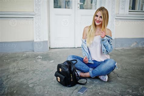 fille blonde porte un jean avec sac à dos posé contre la vieille porte Photo de stock