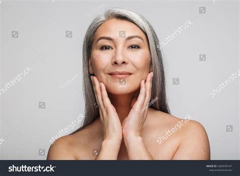 Beauty Portrait Of An Attractive Smiling Mature Topless Woman With Long Gray Hair Standing