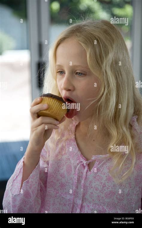 Jeune fille blonde lécher et manger cupcake Photo Stock Alamy