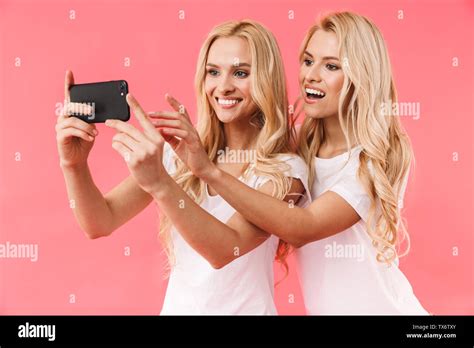 Smiling Blonde Twins Wearing In T Shirts Making Photo On Smartphone