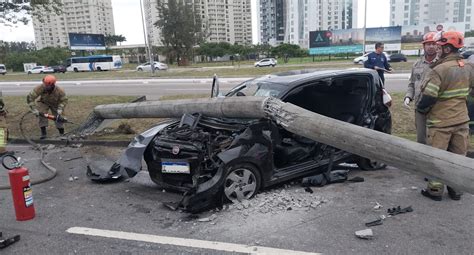 Poste cai sobre carro após acidente na Avenida das Américas