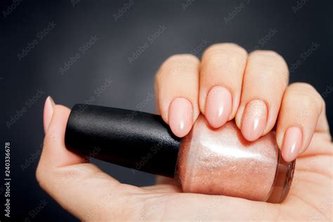 Beautiful Nude Manicure With Gold Decor Womens Hand Holding A Bottle Of Nail Polish Stock Photo