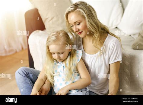 Bonne famille Une jeune mère blonde lit un livre à sa jolie fille tout en étant assise au sol
