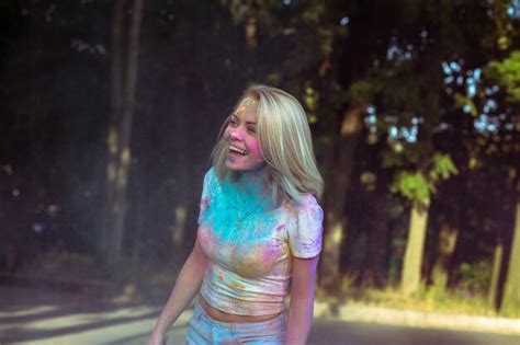 Femme Blonde Souriante Aux Cheveux Flottants Jouant Avec De La Poudre Holi Qui Explose Autour D