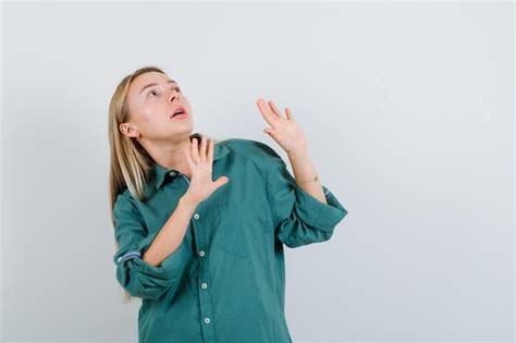 Fille blonde en blouse verte levant les mains pour arrêter et à la peur Photo Gratuite