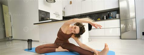 Portrait Of Fit Brunette Woman Fitness Instructor Doing Exercises At Home Stretches Her Legs