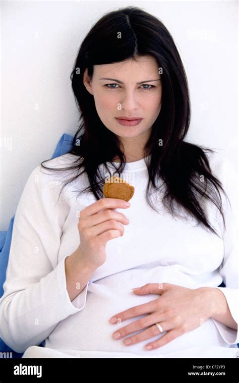 Heavily Pregnant Female Long Brunette Hair Wearing White Longsleeved T Shirt Sitting In Bed