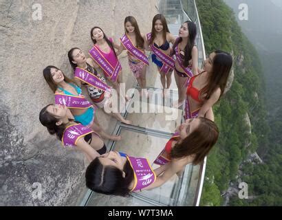 Bikini Dressed Girls Pose On A Glass Walkway Along The Edge Of A Cliff On Baiyun Mountain In